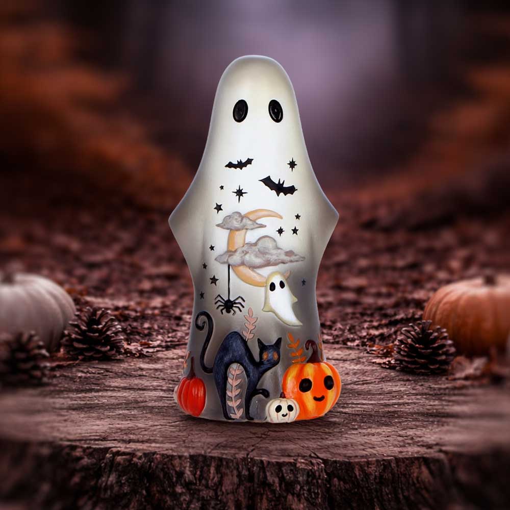 White ghost-shaped decorative candle with pumpkins, a cat, moon, clouds, and bats on a wooden stump.