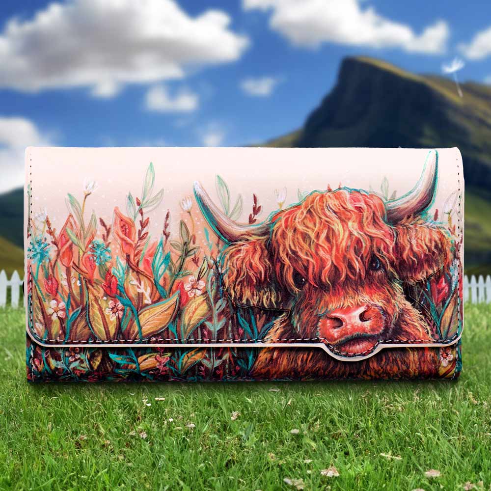 Colorful wallet featuring a cow's face among bright wildflowers with a grassy meadow and blue sky in the background, in watercolor-style art.