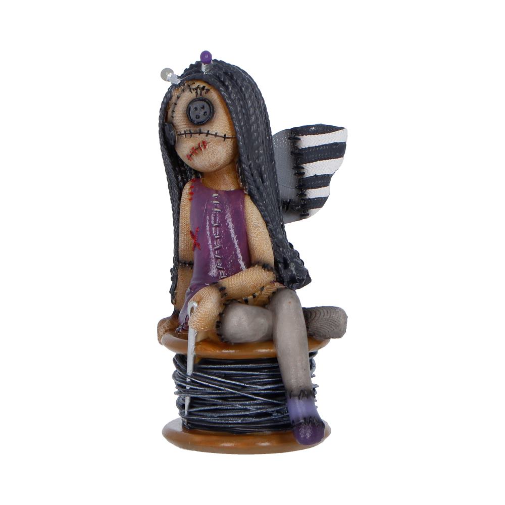 Handmade whimsical fairy figurine with button eye and stitched mouth, wearing a purple dress and striped wings, sitting on a spool of thread.