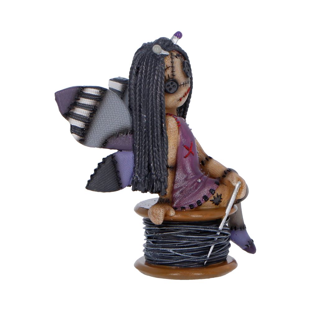 Small handmade zombie girl figurine sitting on a spool of thread with a needle