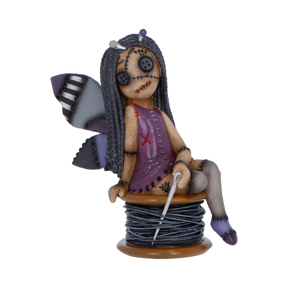 Fabric fairy doll with stitched face and purple dress sitting on a thread spool, holding a needle and thread.