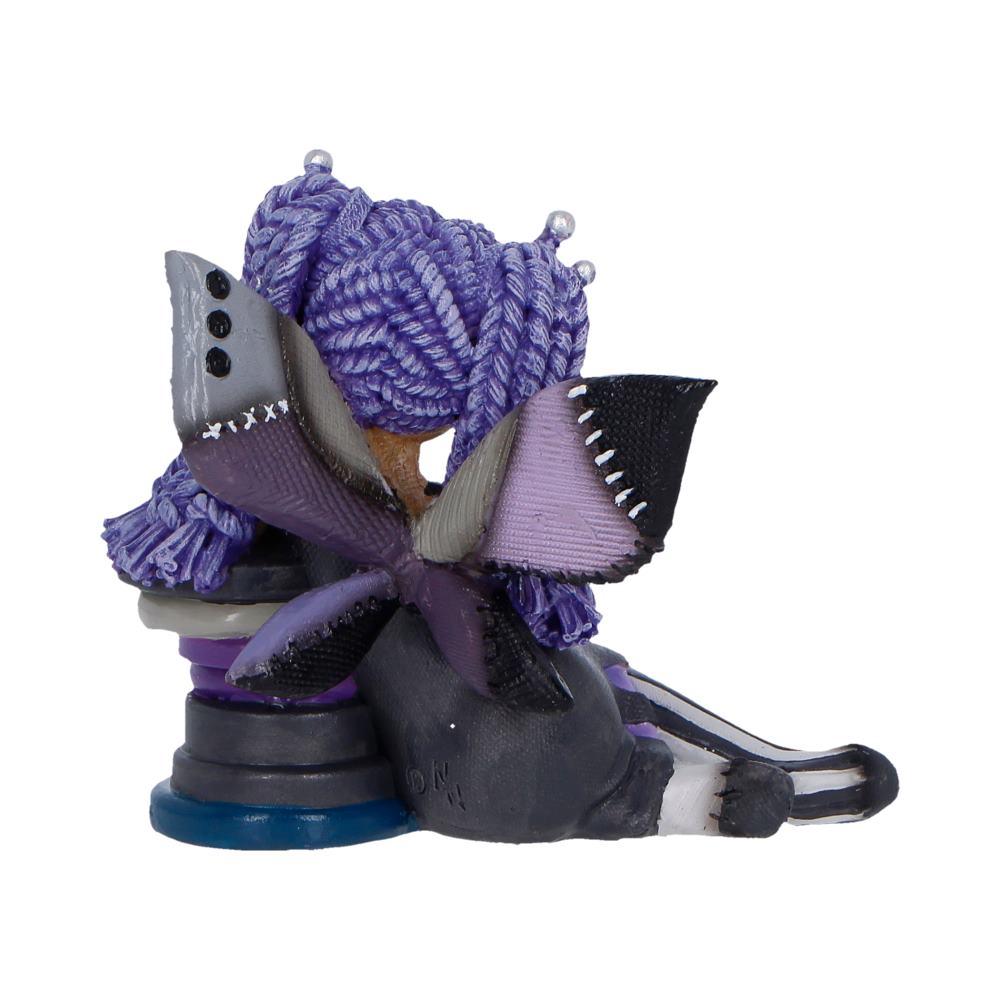 Abstract mixed-media sculpture of a purple-haired creature with fabric wings perched on stacked circular bases.