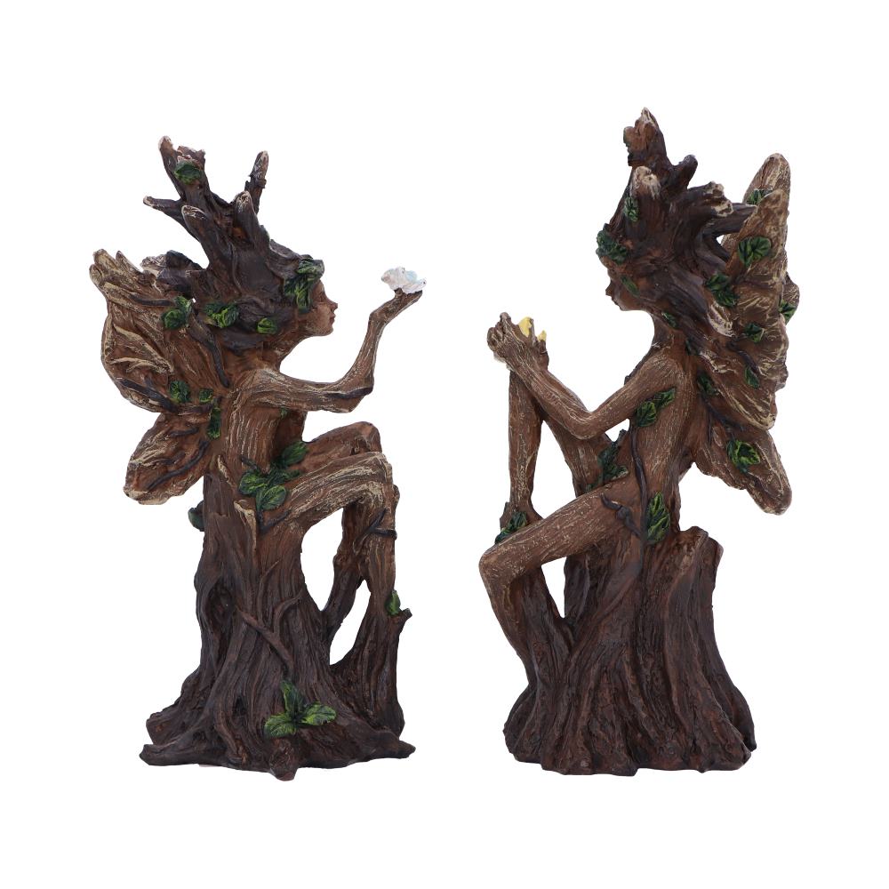 Two decorative tree-spirits statues perched on stumps, facing each other with raised arms holding small objects.