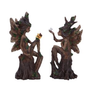 Two woodland fairy statues perched on tree stumps, exchanging a small white bird.