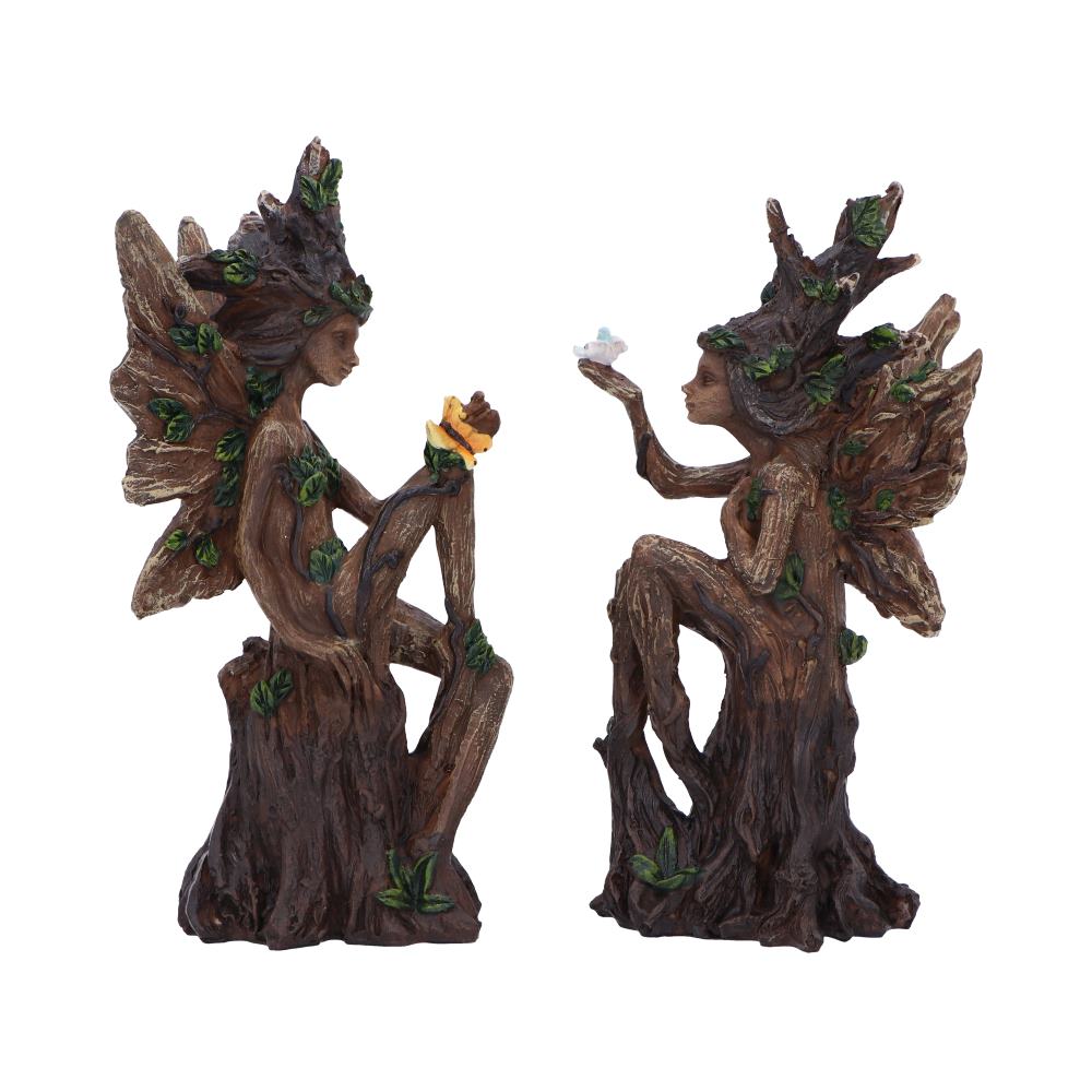 Two woodland fairy statues perched on tree stumps, exchanging a small white bird.