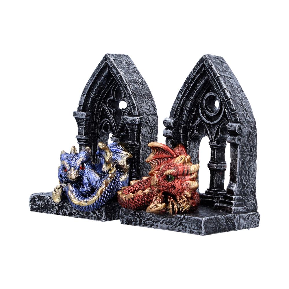 Two dragon statues resting in front of a dark grey, Gothic-style ruined archway.
