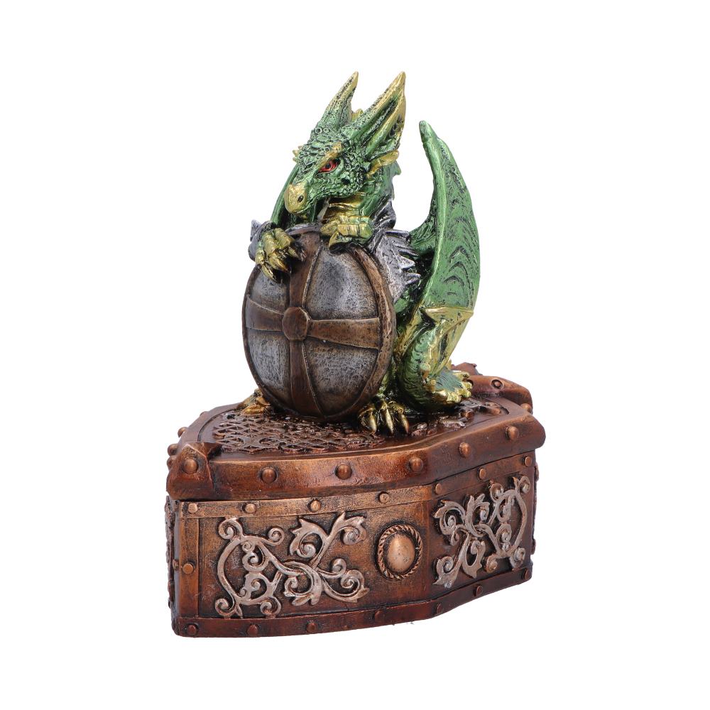 Green dragon figurine perched on a brown ornate treasure chest, gripping a round shield with riveted bands.